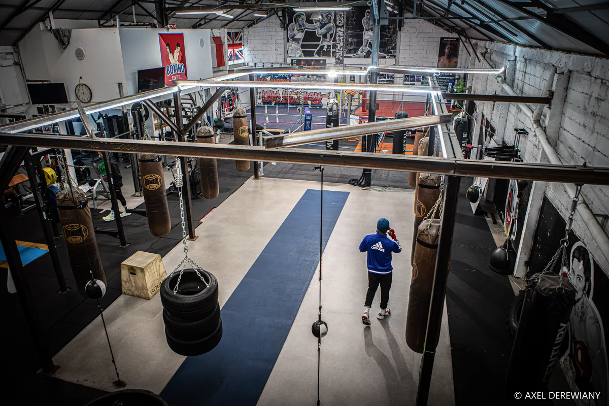 Vue plongeante sur la salle de boxe des Minimes : le tapis central, les sacs de frappe alignés et la charpente en verrière